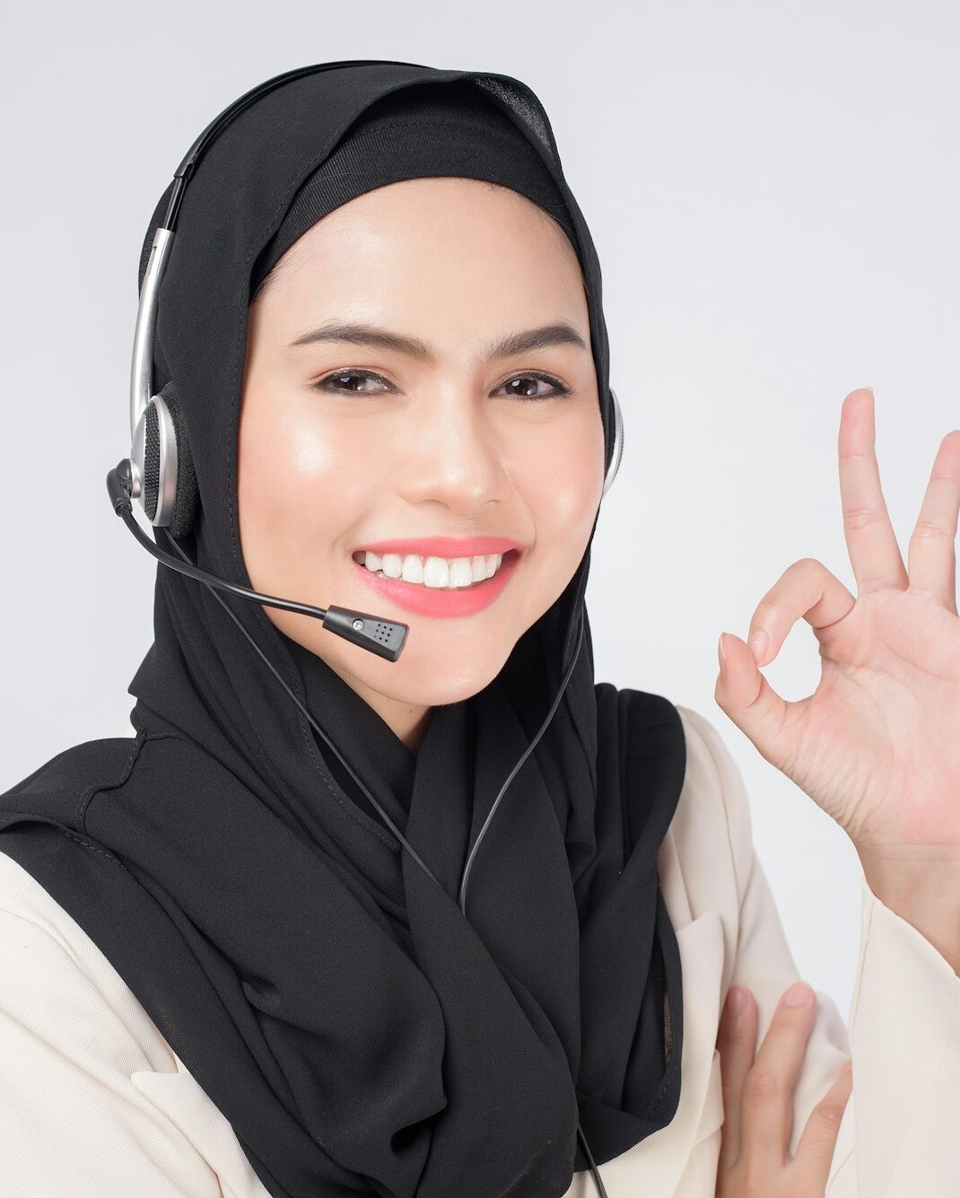 Customer service operator muslim woman in suit wearing headset over white background studio.